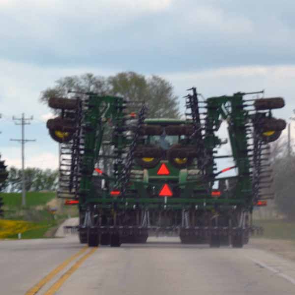 A color photo of a farm tractor towing a piece of tillage equipment