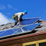 Man on residence rooftop installing solar panels