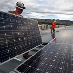 worker's installing solar panels on industrial roof