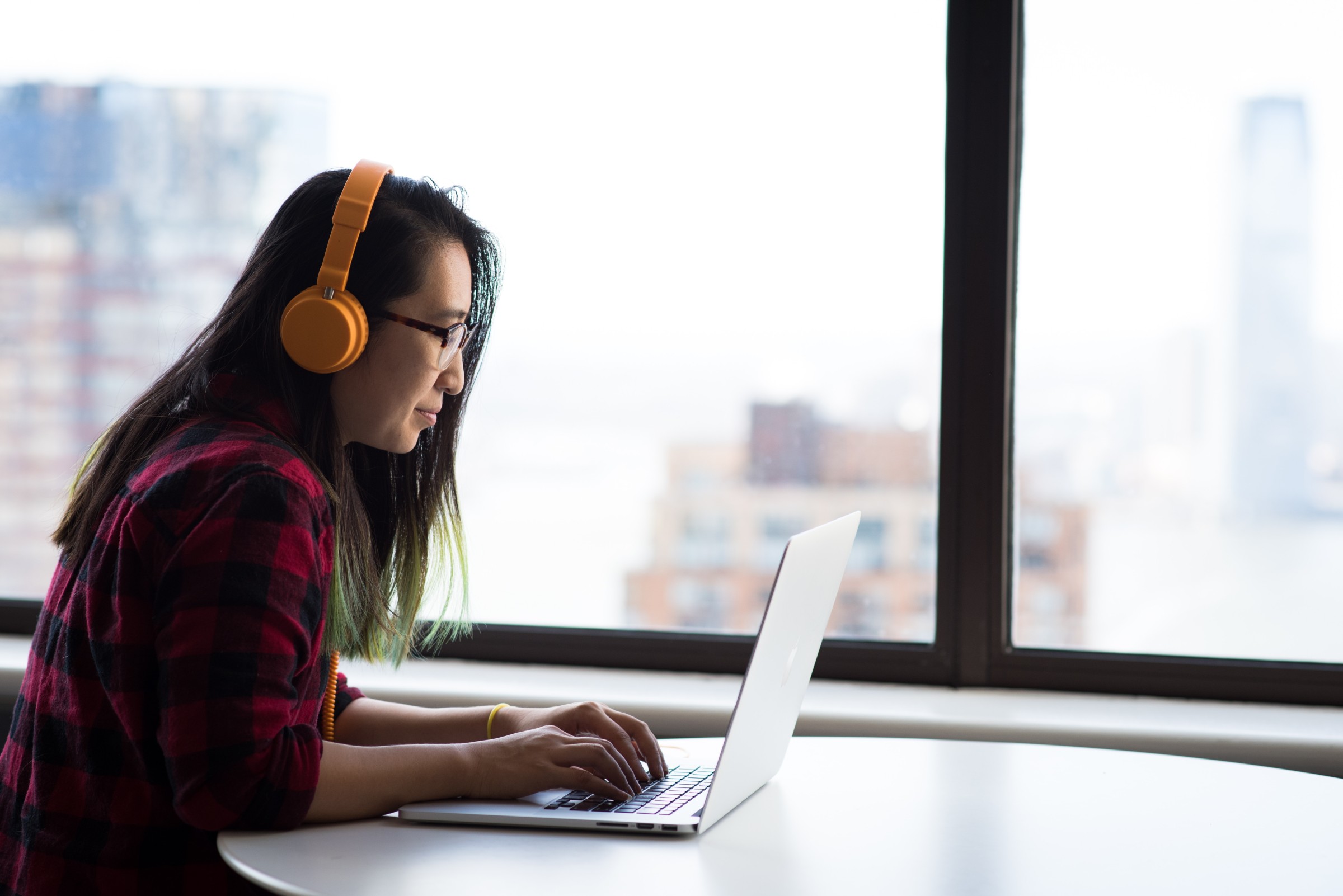 woman with headphones watching instructional video on laptop