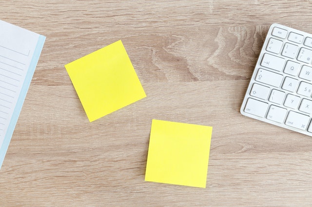 desk with yellow note pads and white keyboard