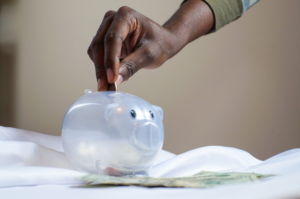 Man inserting coins to a piggy bank