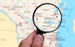 Map of Wisconsin with a magnifying glass over cities.