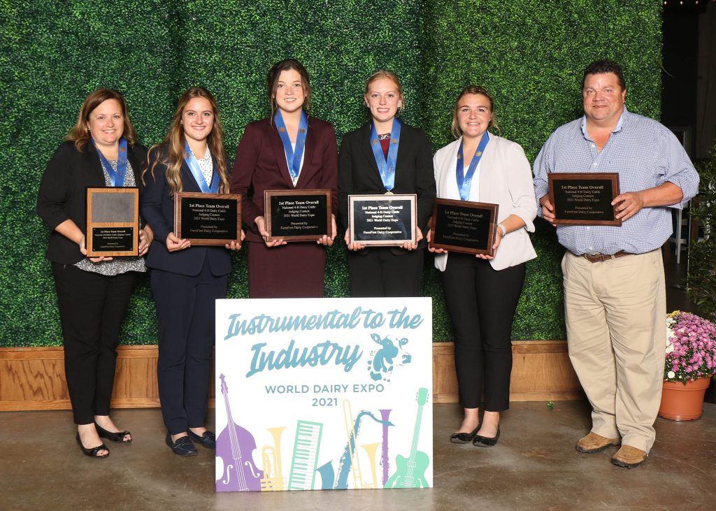 Group of adults and youth holding plaques and wearing medals for winning a national award for Dairy Judging in 4-H