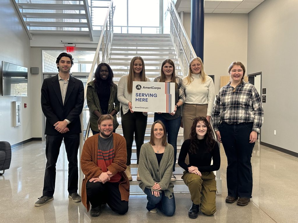 Wisconsin 4-H AmeriCorps members hold sign that says "Serving Here"