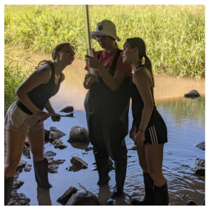 Three students look at a tube to measure water quality