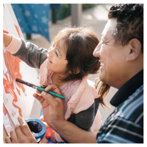 Father and daughter paint together.