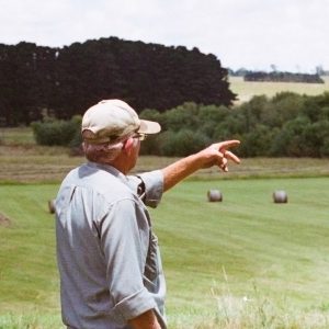 Man overlooking green pasture with hay bales