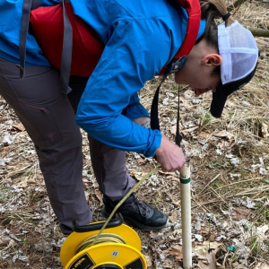 Hydrogeologist bent over putting tube into ground