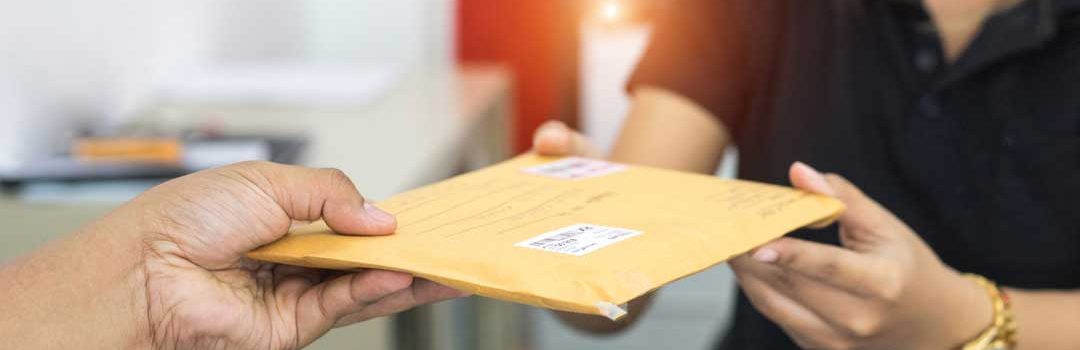 Two people exchanging a large envelope which has been mailed.