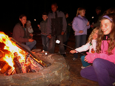 Children and families roasting marshmallows on a campfire