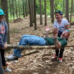 This image shows Clinton Middle schoolers carrying their teacher on a stretcher that they built themselves out of logs and string.
