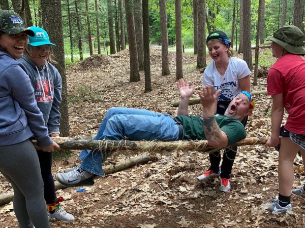 This image shows Clinton Middle schoolers carrying their teacher on a stretcher that they built themselves out of logs and string. 